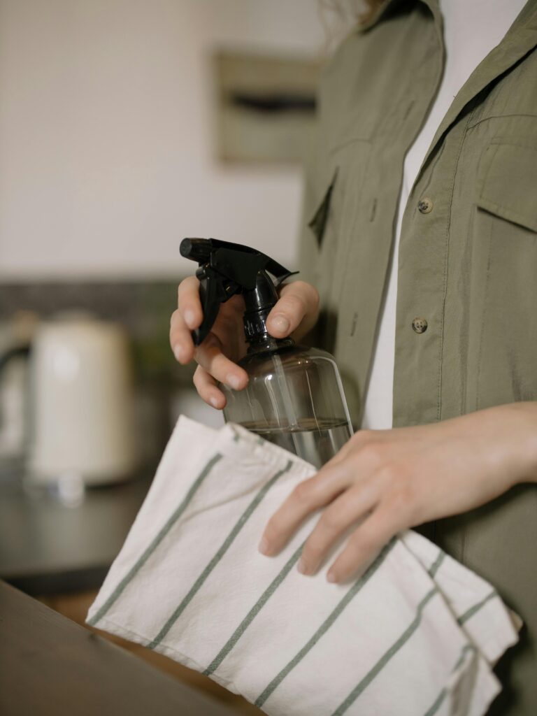 Close-up shot of a person cleaning with a spray bottle and cloth. Ideal for cleaning and home care themes.